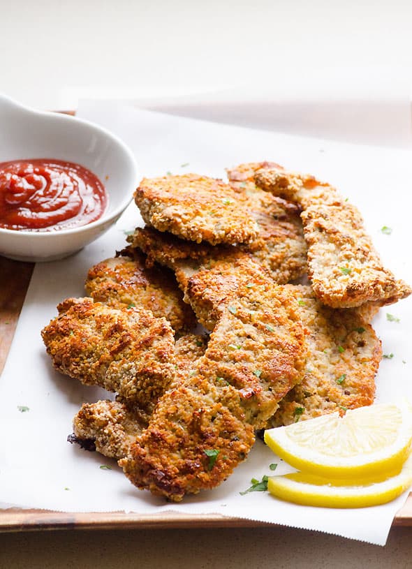 Almond crusted chicken on a platter with ketchup for dipping.