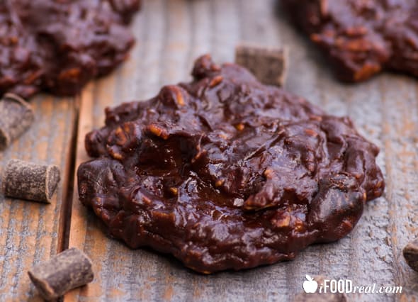 Chocolate protein cookies with chocolate pieces on wood counter.