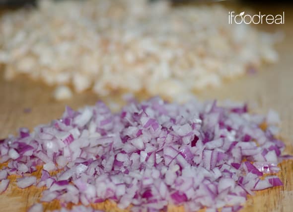 Chopped red onion and garlic on cutting board