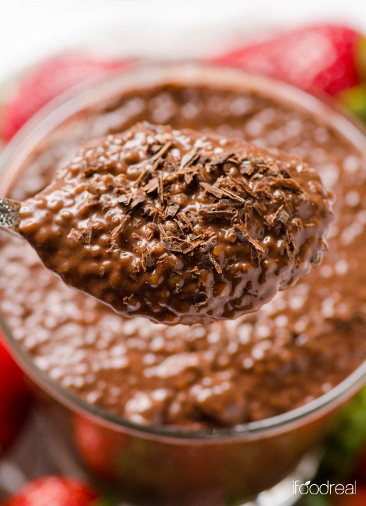 Chocolate chia pudding on a spoon with chocolate shavings.