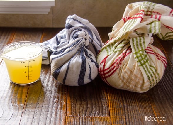 Cauliflower rice wrapped in two towels with measuring cup that has liquid squeezed from it.