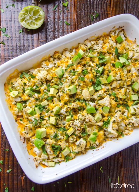 A baking dish with roasted cauliflower with cheese, avocado and cilantro.