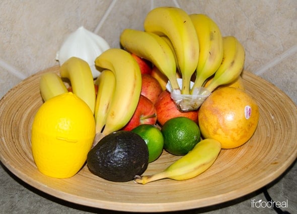 Plate of bananas, oranges, lime, avocado, lemon and apples