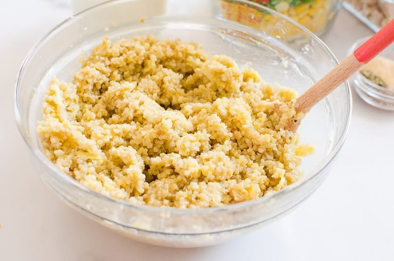 Quinoa topping with eggs and cheese in a bowl with a spoon.