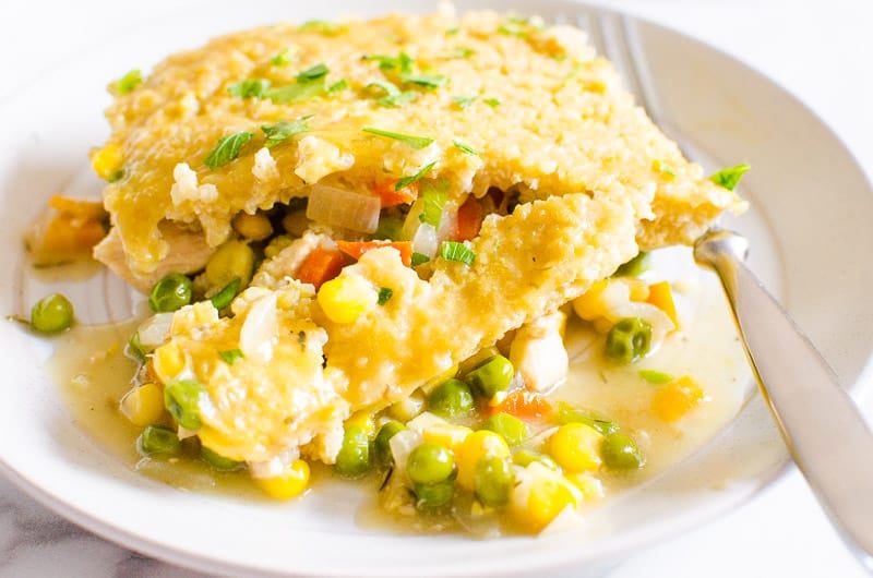 Healthy chicken pot pie with veggie filling of peas carrots and corn plated with a fork.