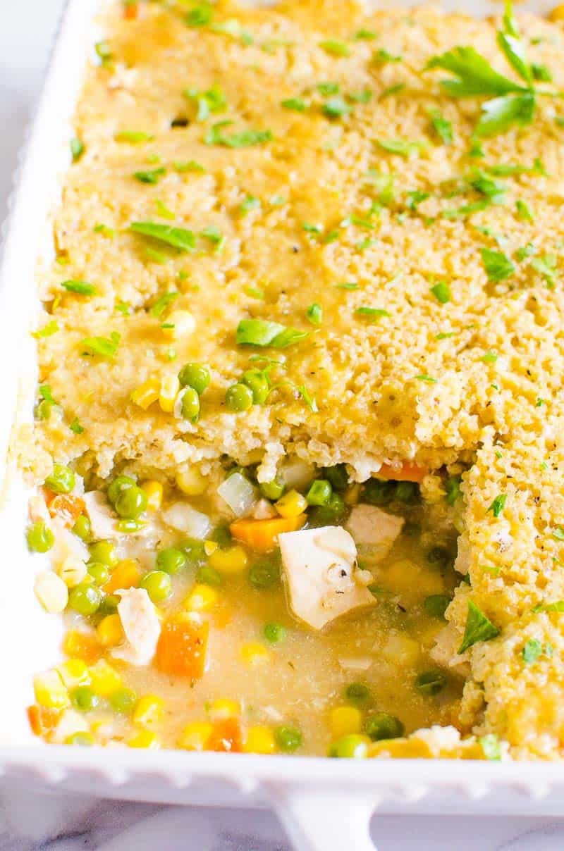 Healthy Chicken Pot Pie in baking dish with a square cut out showing chicken peas carrots and corn.