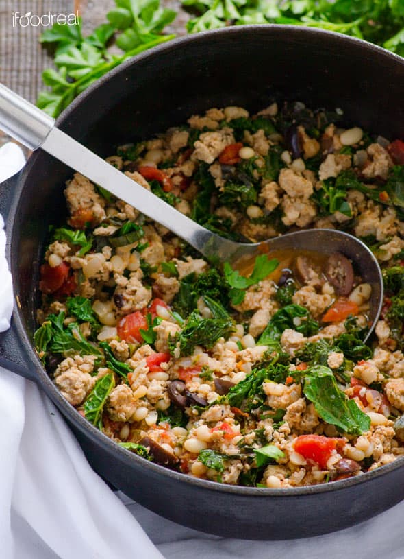 Kale, beans, and turkey in pot with a ladle.