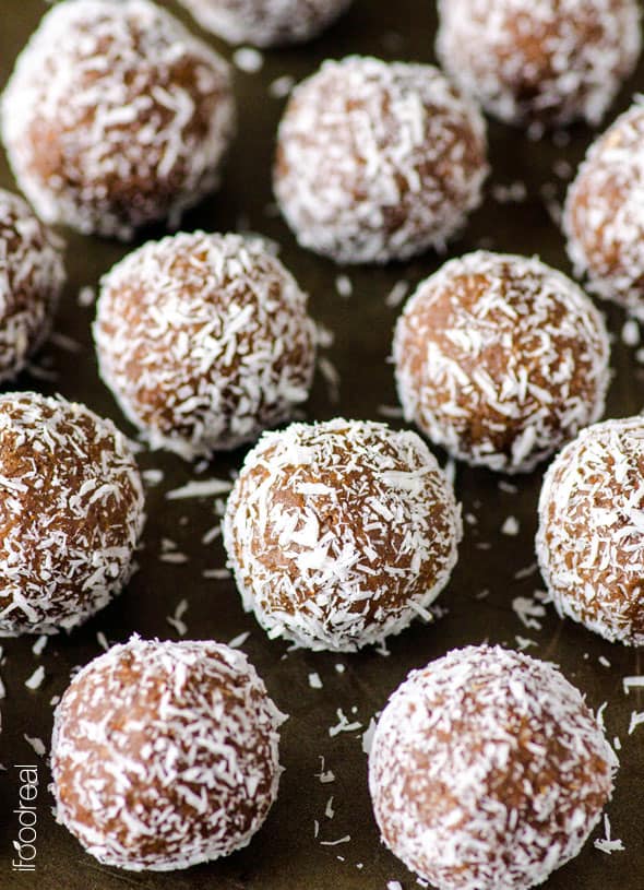 Almond Joy Protein Balls rolled in coconut flakes on a dark surface.