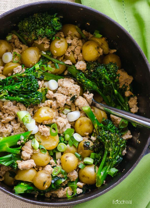 Ground Turkey, potatoes and broccoli in a skillet with green linen.