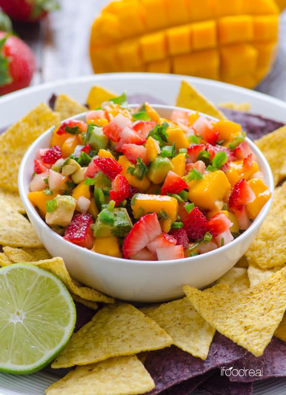 Strawberry mango salsa in a bowl with chips on a platter. 