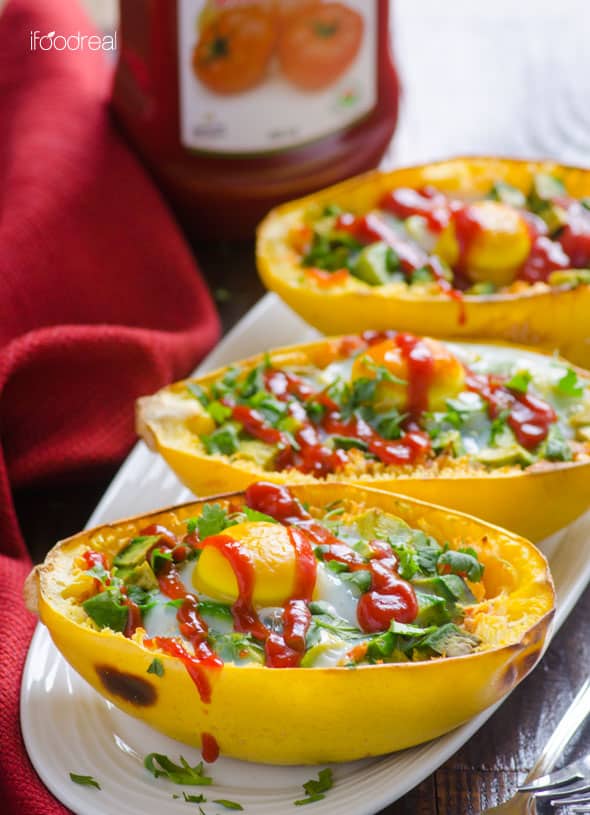 Spaghetti squash as bowls filled with cooked spaghetti squash egg and avocado with drizzle of ketchup. 