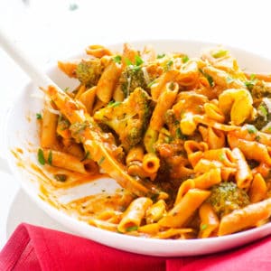 Broccoli and penne pasta on serving plate with spoon.