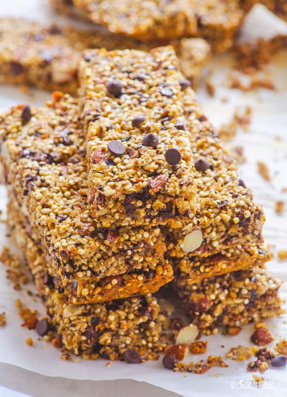 Quinoa granola bars stacked on top of each other on parchment paper.