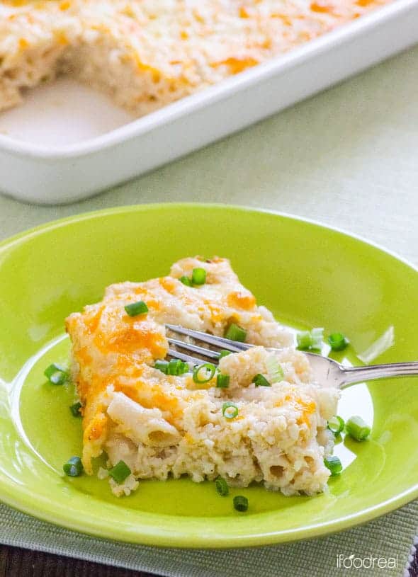 A slice of baked mac and cheese garnished with green onions on green plate.