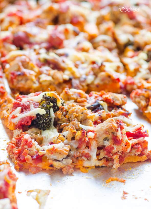 A slice of sweet potato pizza crust with ground turkey, broccoli, cheese and tomato sauce on a baking sheet.