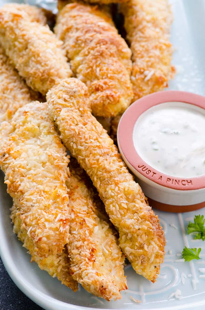 crispy coconut chicken tenders on a plate with a side of dipping sauce