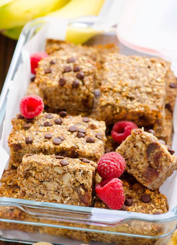 Healthy banana oatmeal bars cut in squares in baking dish with fresh raspberries.