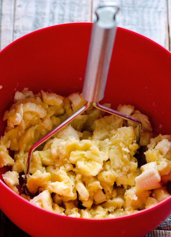 Mashing bananas in a red bowl.