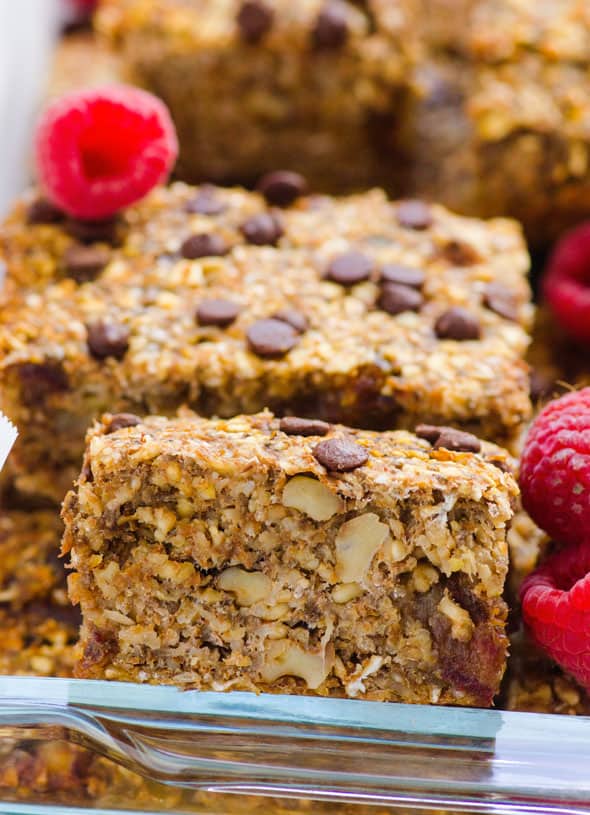 Healthy banana oatmeal bars cut into squares in a baking dish with fresh raspberries.