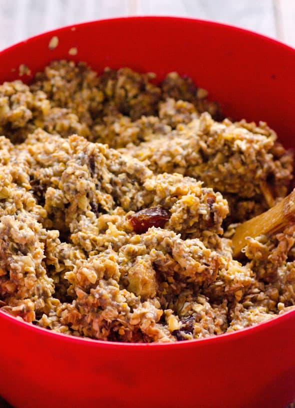 Batter with bananas, applesauce, milk, oats, flax, dates and walnuts in red bowl.