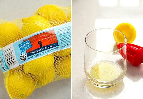 A bag of lemons and lemon squeezer with lemon juice in a glass.