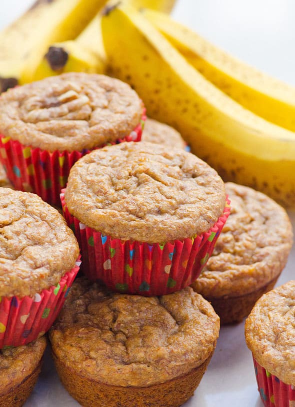 stack of healthy banana muffins with red liners and fresh bananas