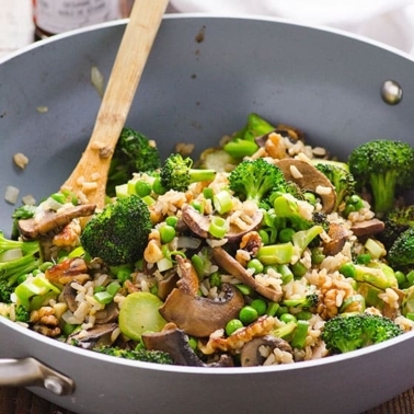 Broccoli mushroom stir fry in a wok with wooden spoon and garnished with green onions.