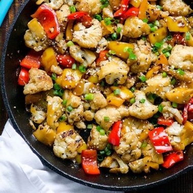sesame cauliflower in a sticky sauce bell peppers in cast iron skillet with white linen