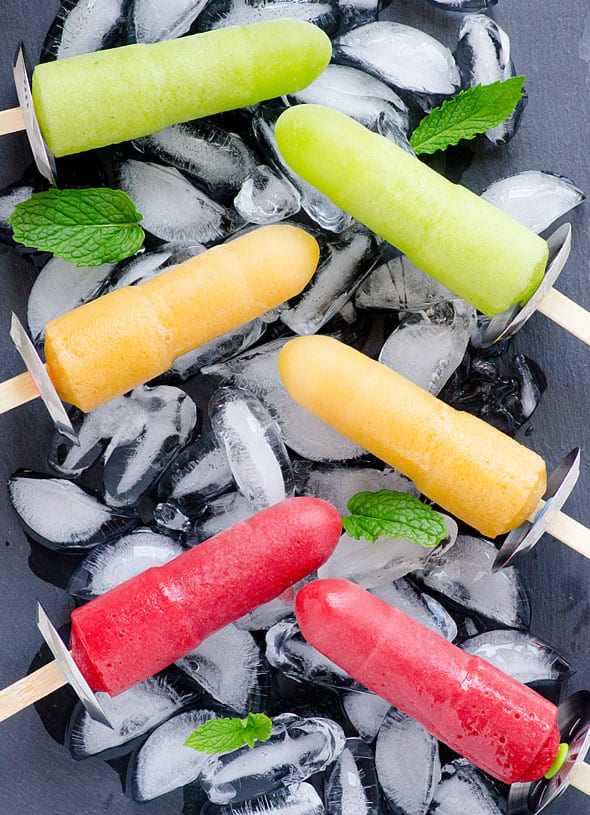 Six healthy homemade popsicles on ice with mint leaves.