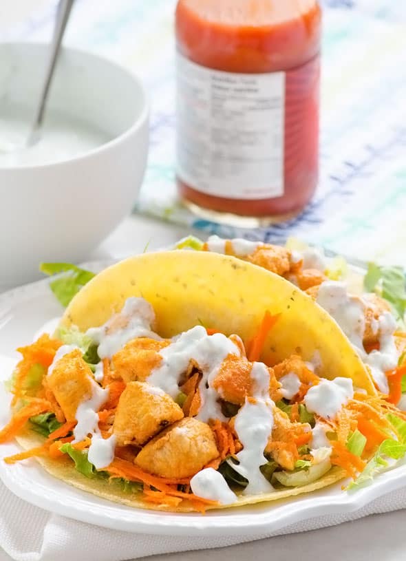Buffalo chicken tacos in tortillas drizzled with healthy blue cheese sauce.
