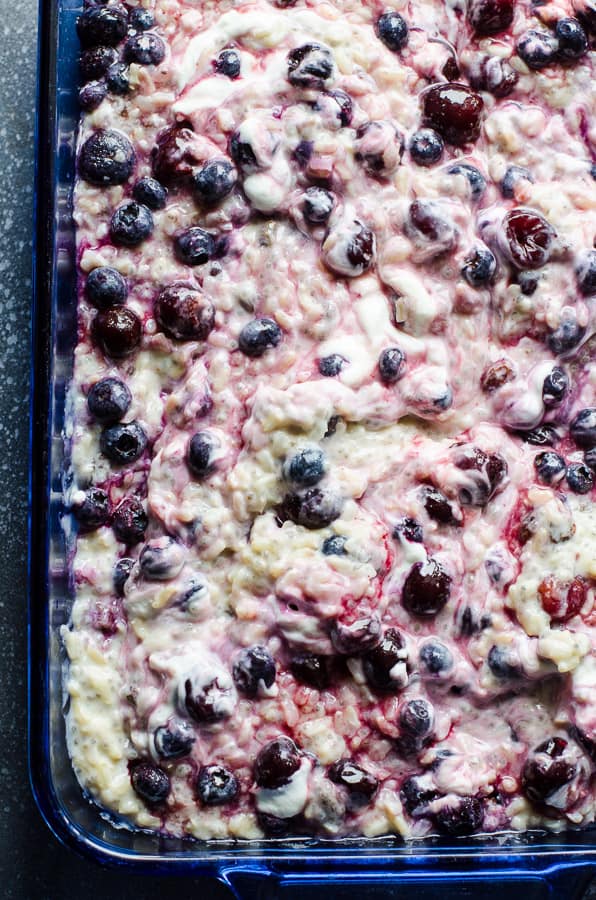 Brown rice pudding with fruit and yogurt in blue glass baking dish.