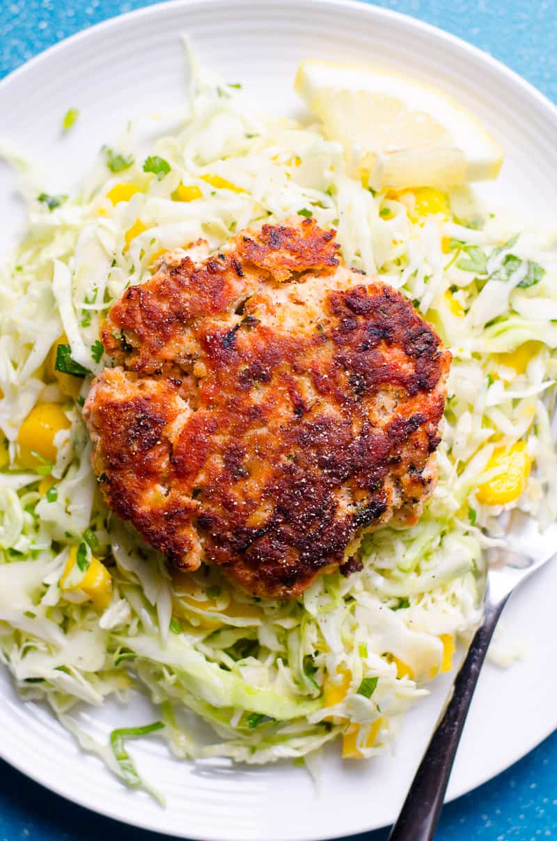 salmon burger on a plate served over mango coleslaw