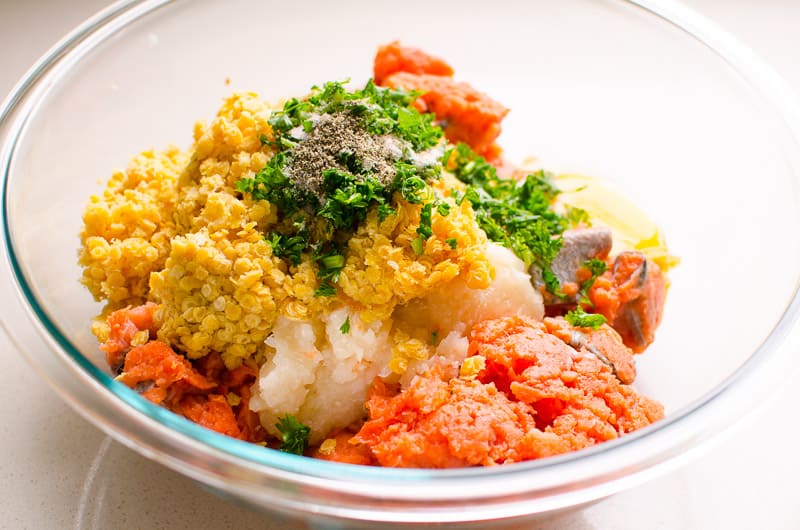 Ground salmon, red lentils, parsley, onion and spices in glass bowl.