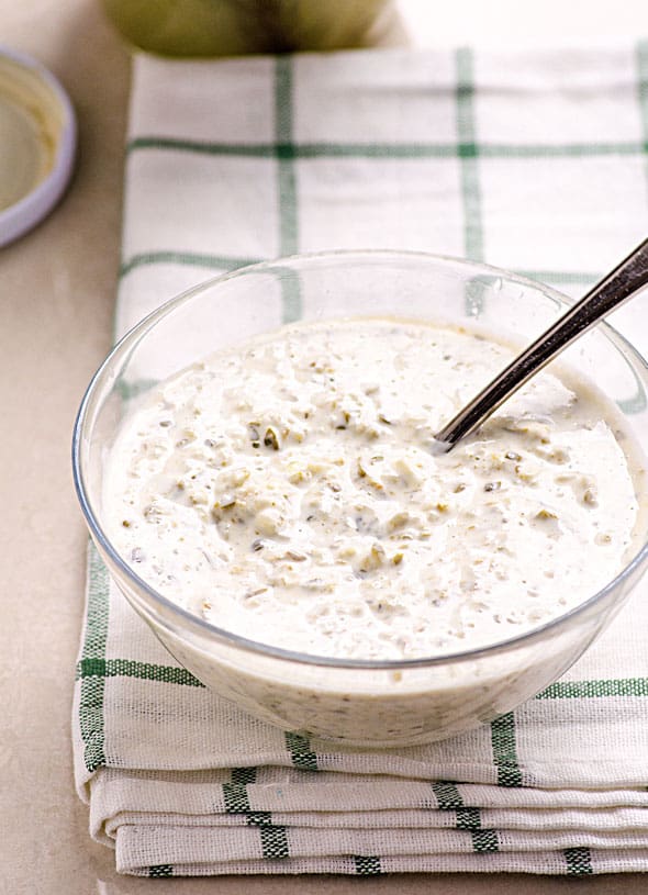 Greek yogurt tartar sauce in a glass bowl with a spoon.