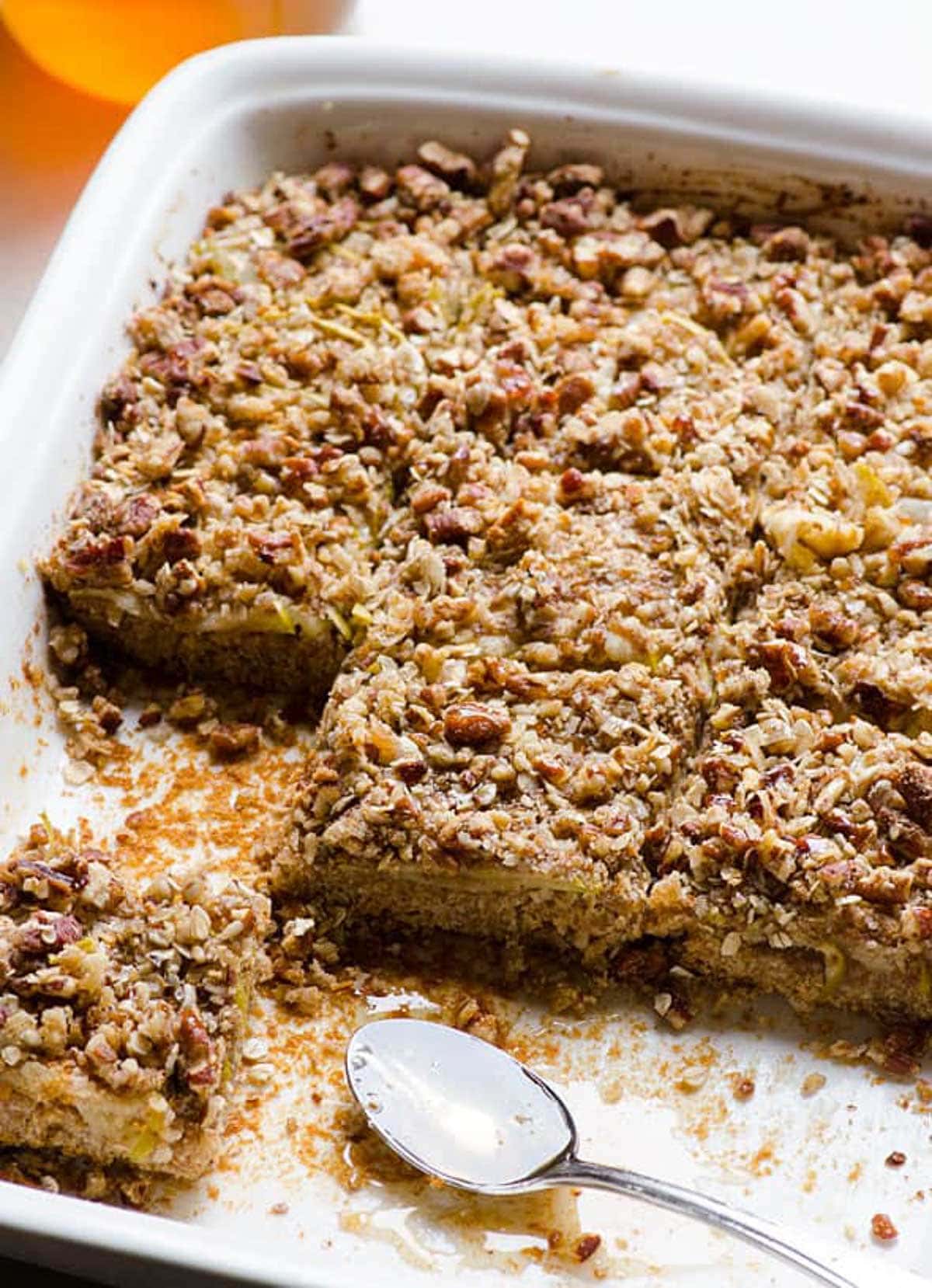 Healthy apple oatmeal bars cut into squares in baking dish with spoon.