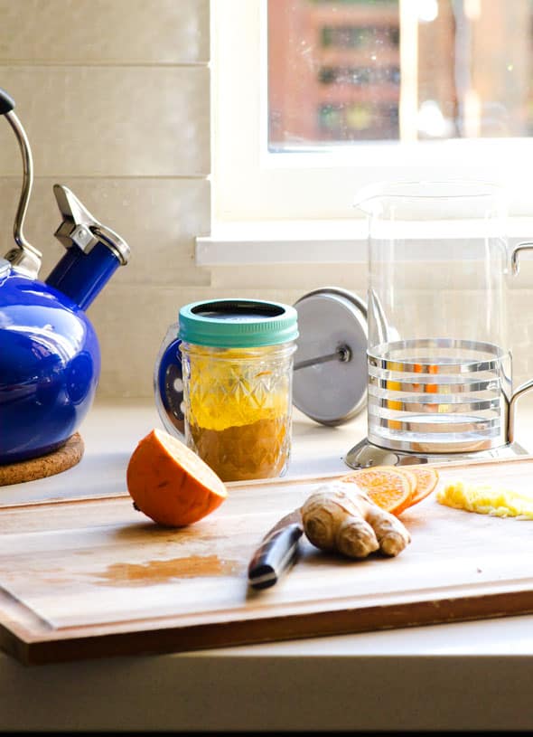 Orange, ginger, turmeric, kettle, French Press, cutting board and knife.