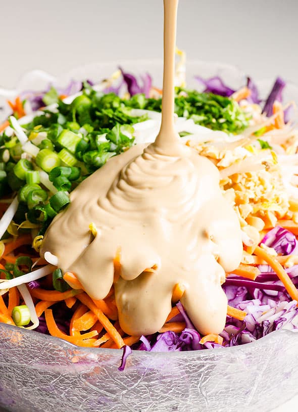 Peanut sauce being drizzled on salad.