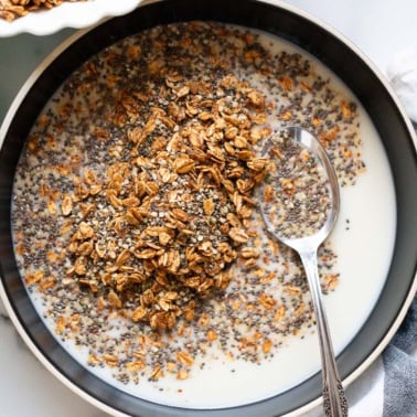 A bowl with healthy homemade cereal with milk and a spoon.