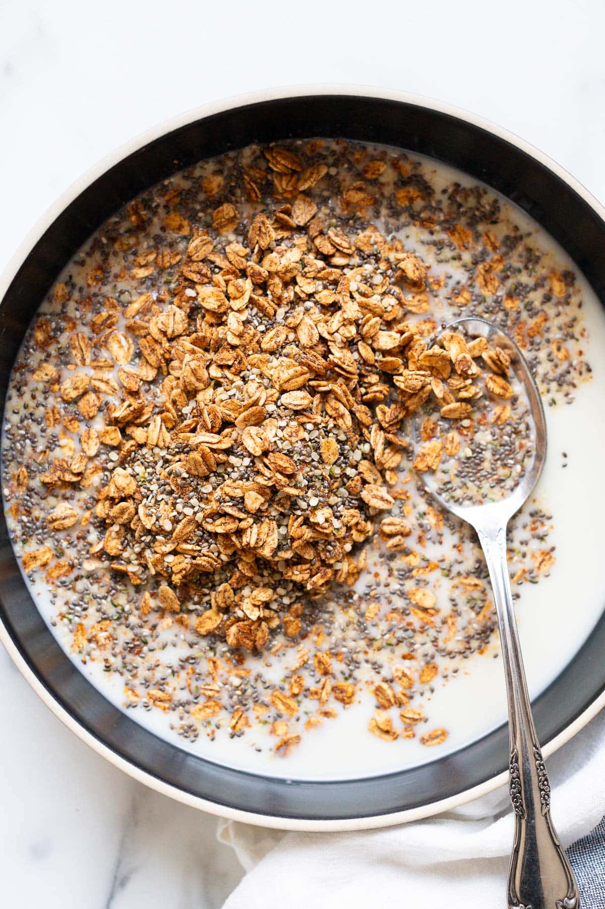 A bowl with healthy homemade cereal with milk and a spoon.