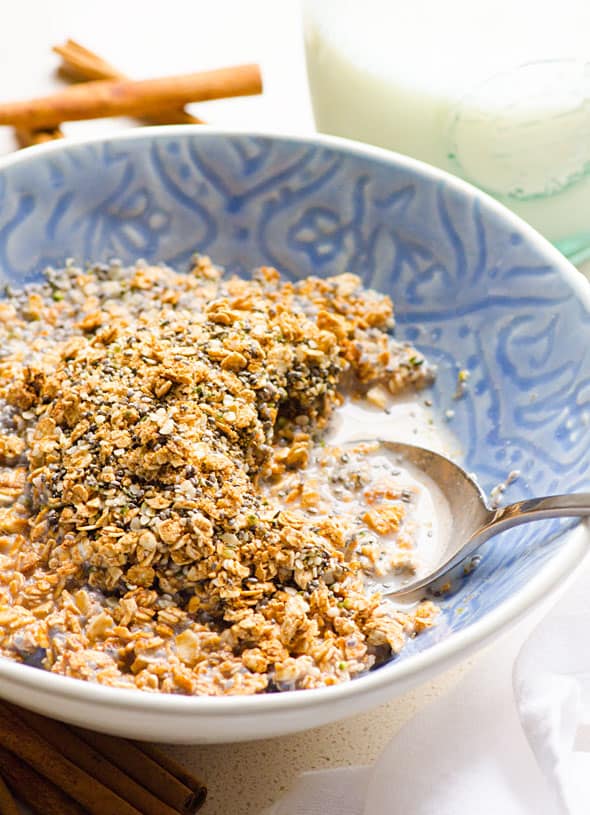 A bowl with healthy homemade cereal with milk and a spoon.