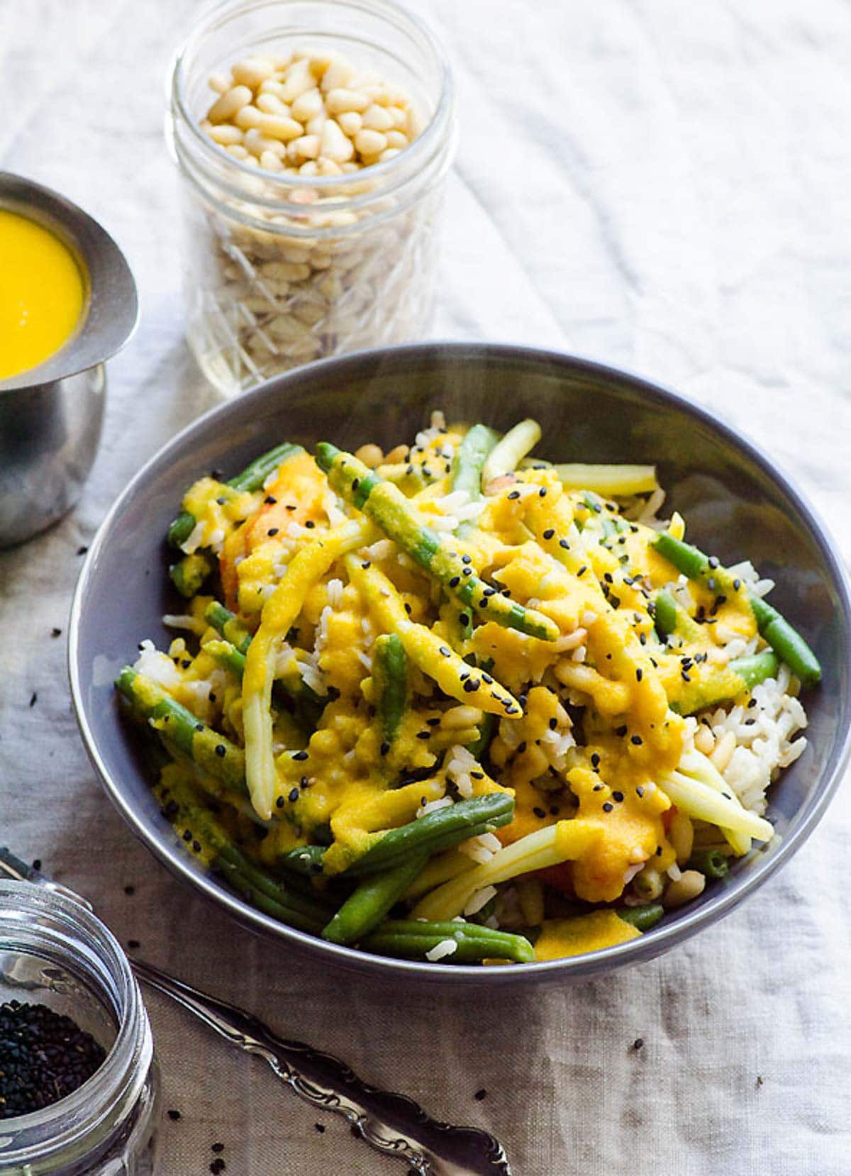 Japanese carrot ginger dressing on top of bowl of asparagus and rice topped with black sesame seeds.