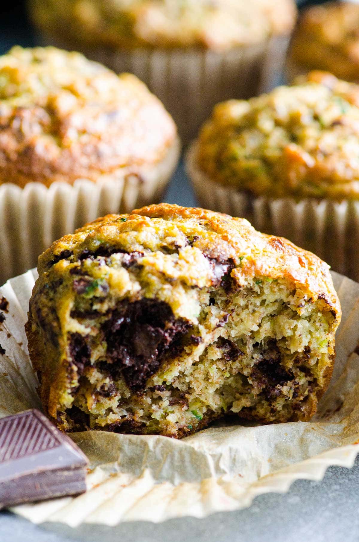 Banana zucchini muffins with one unwrapped and a bite missing.