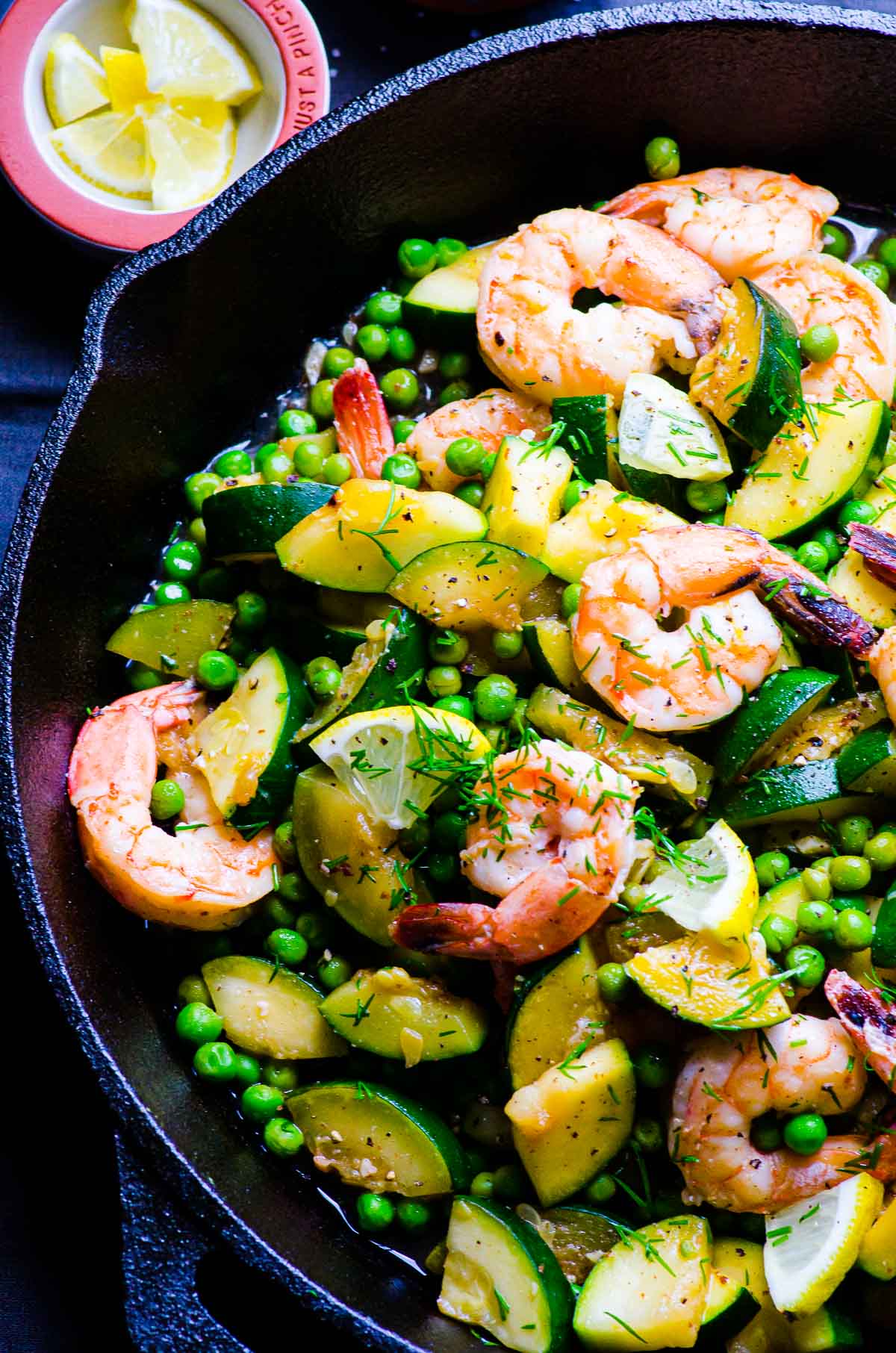 Shrimp with zucchini in cast iron skillet with dill, peas and lemon.