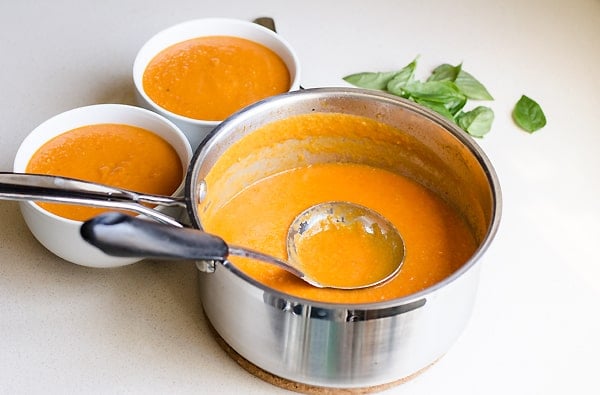 pot of Sun Dried Tomato Soup with ladle beside two bowls of soup