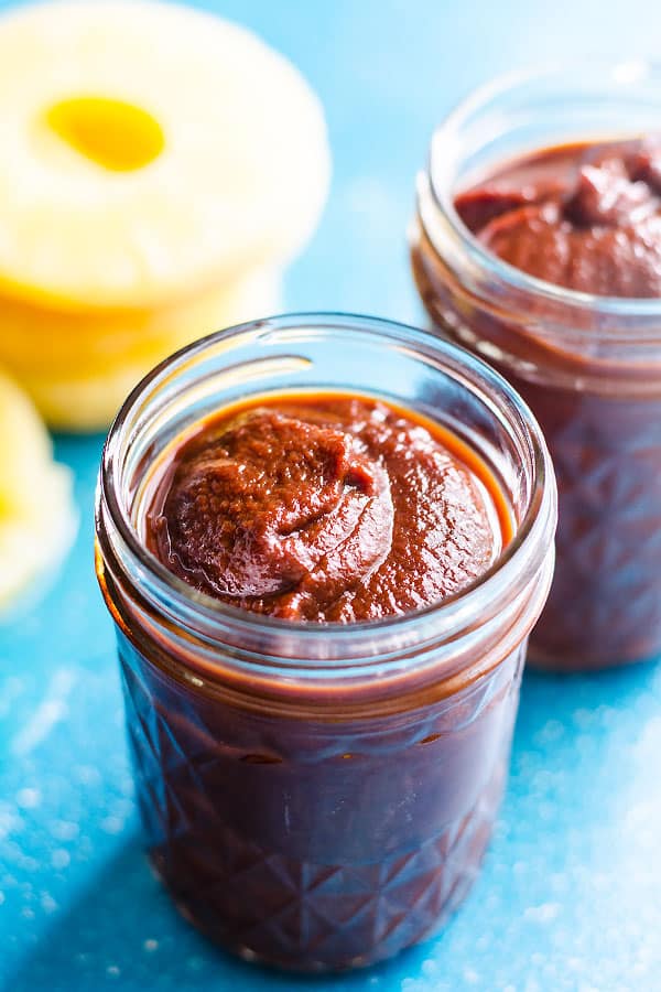 Hawaiian BBQ sauce in glass jars with pineapple slices on the counter.
