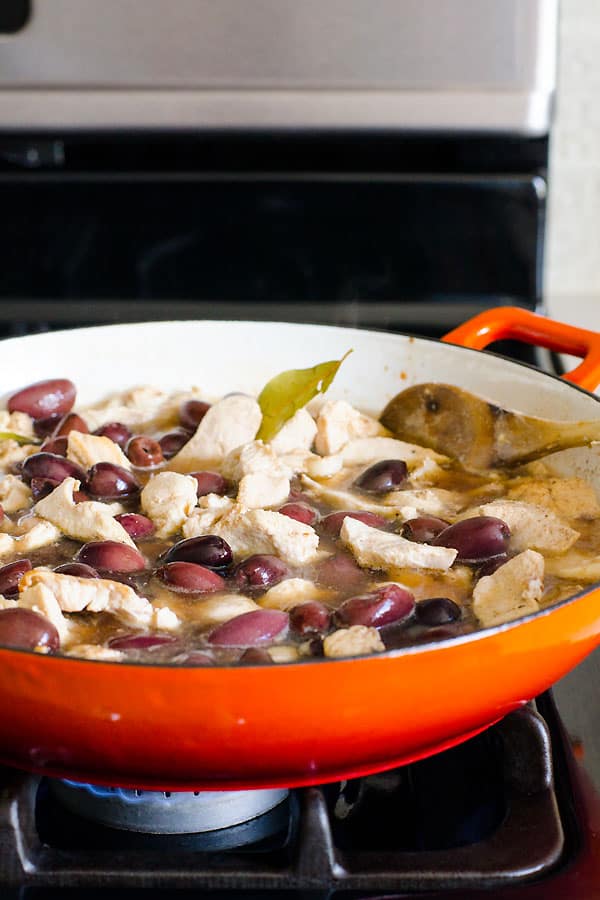 chicken simmering with and olives on the stove