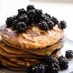A stack of healthy peanut butter protein pancakes with blackberries.