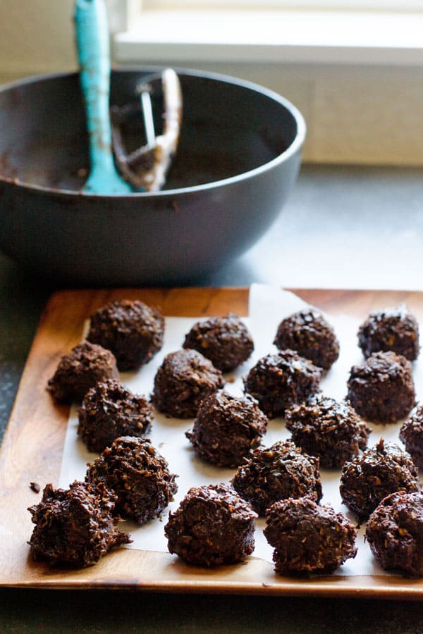 Chocolate coconut balls on a platter with mixing bowl behind.