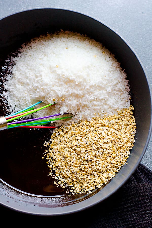 Coconut flakes, oats and chocolate liquid mixture in a bowl.