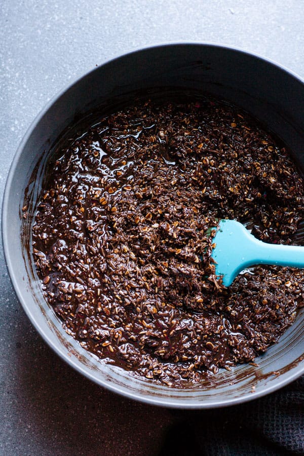 A bowl of chocolate, coconut, and oats with blue spatula.